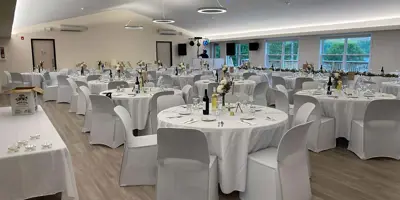 Event area decorated for wedding with head table and rounds of tables.