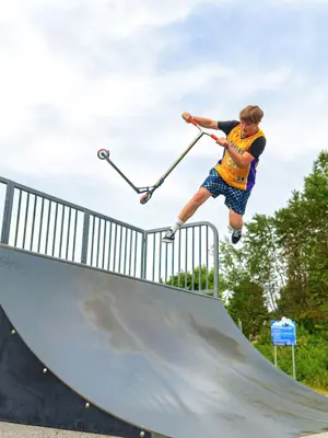 Skateboarder on a scooter doing an aerial manouver.