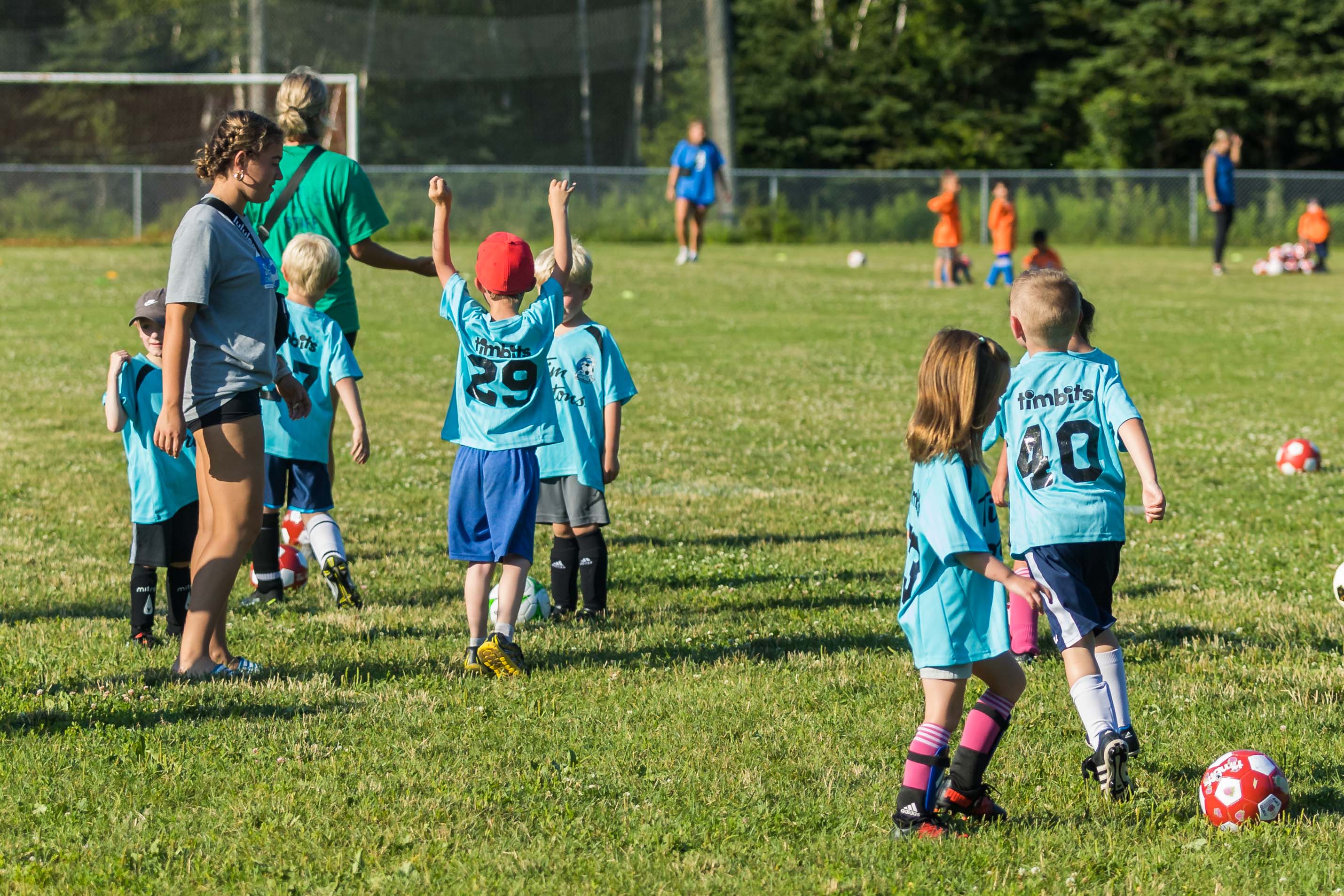 Kids kicking around the soccer ball on field. 