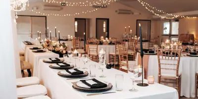 Event area decorated for wedding with head table and rounds of tables.