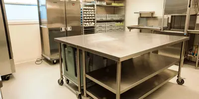 Kitchen with commercial fridge, stove, plates.