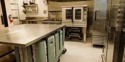 Kitchen with commercial fridge, stove, plates.