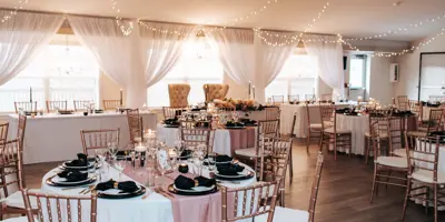 Event area decorated for wedding with head table and rounds of tables.